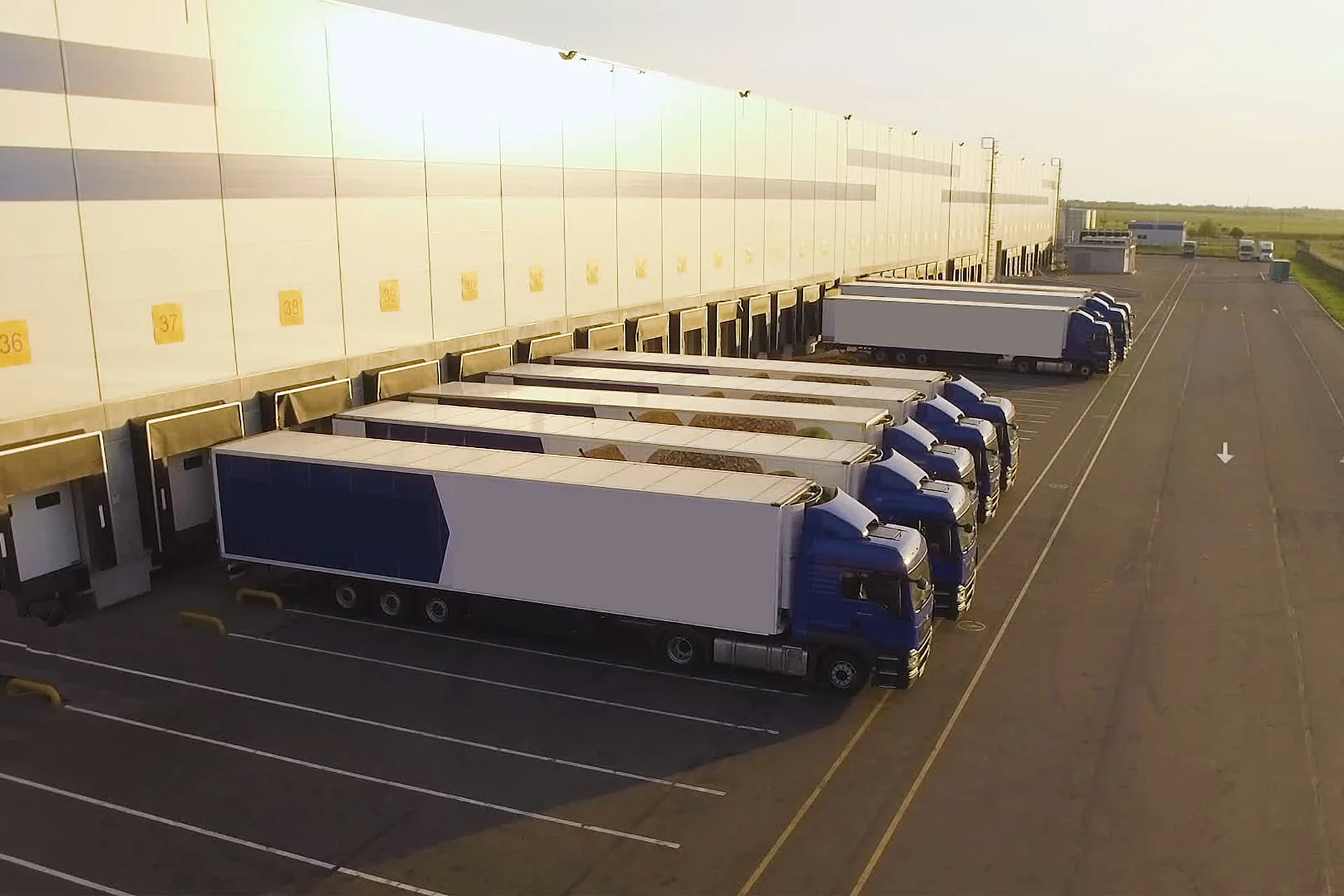 Row of trucks in front of a warehouse loading and unloading goods