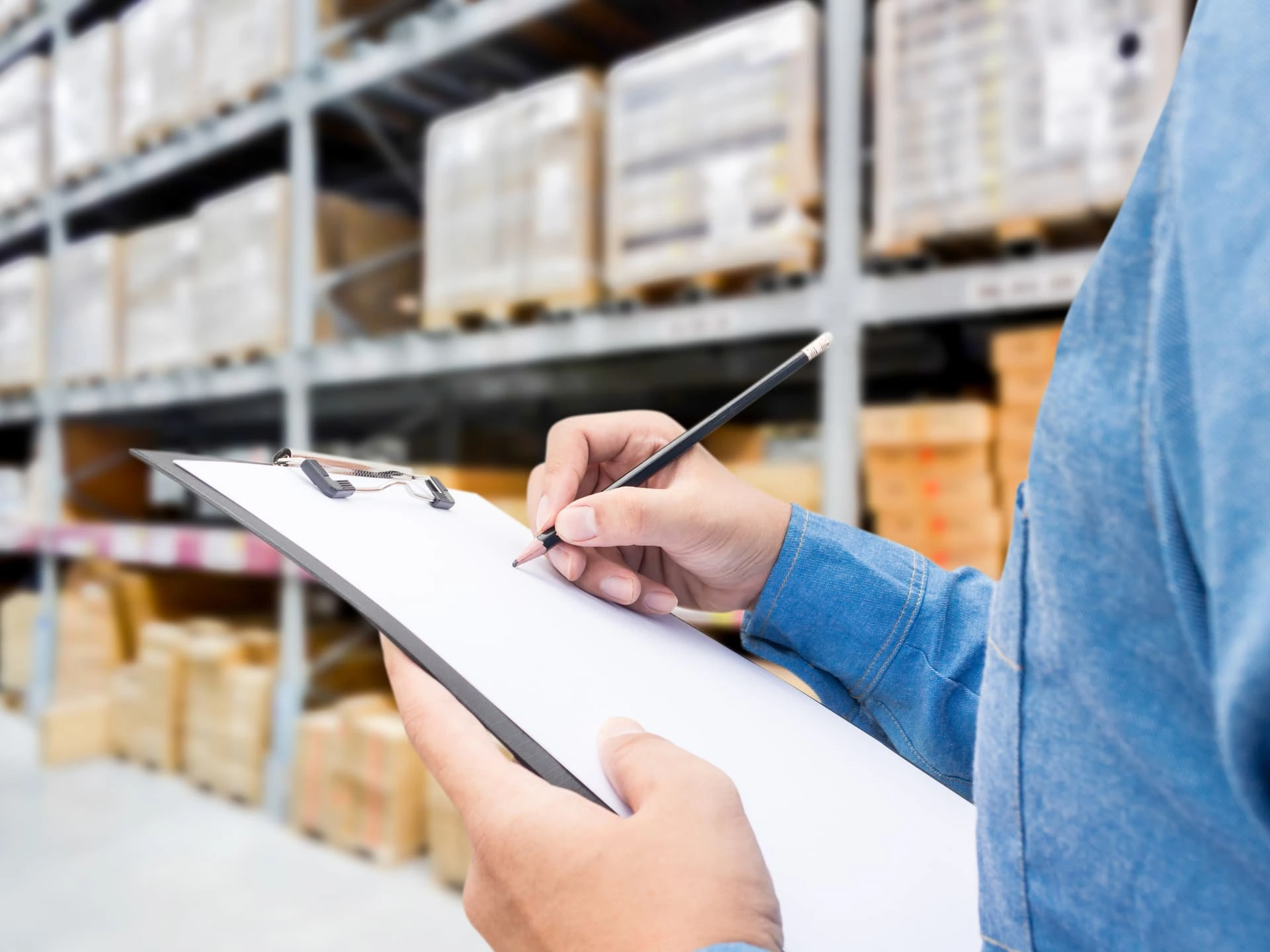Person carrying out an inspection in a warehouse with pallets