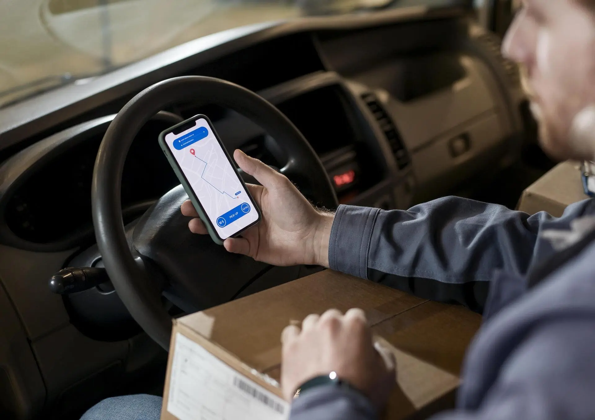 In a car, a delivery driver follows the route of his order from his phone