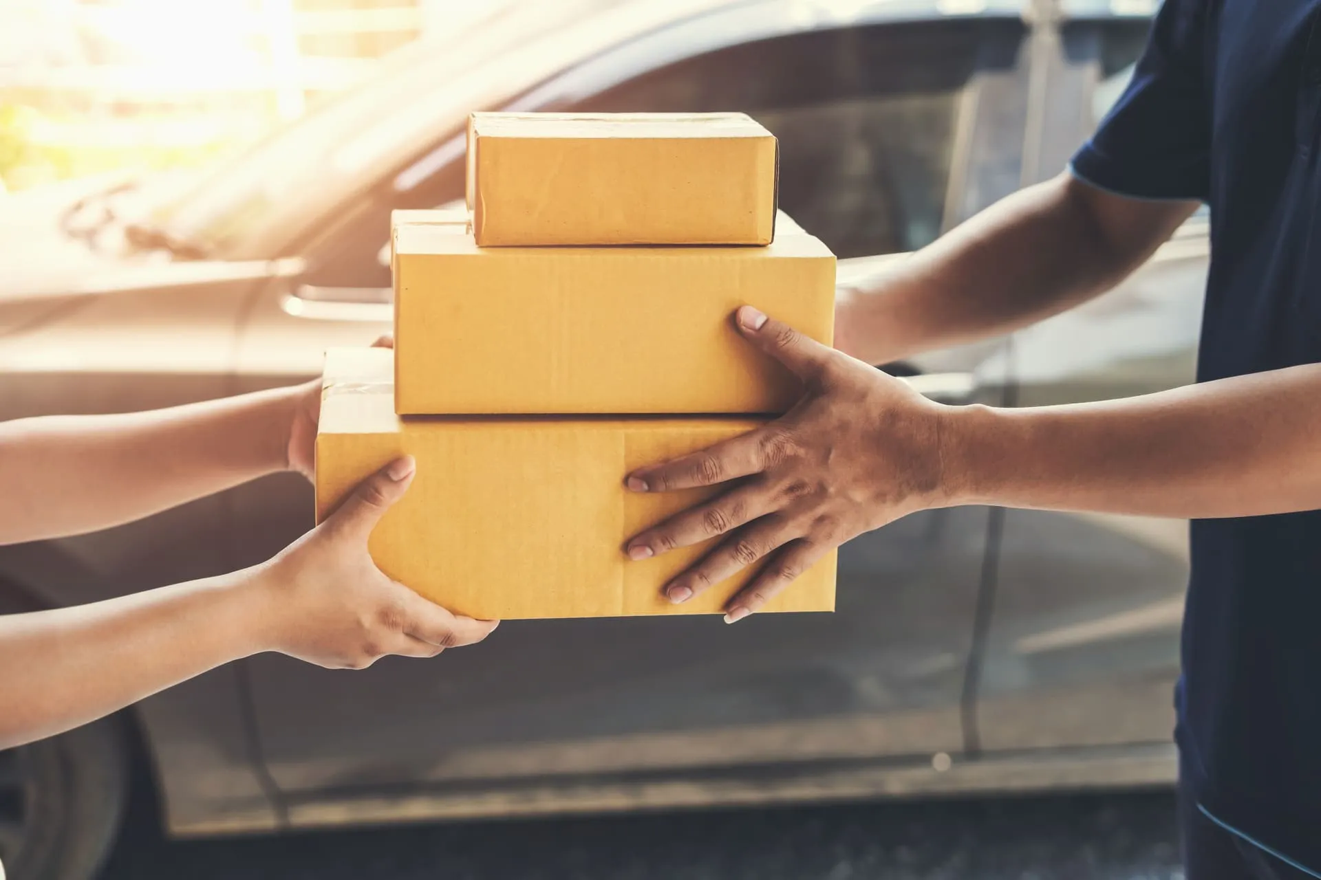 Livreur donnant trois colis à un client