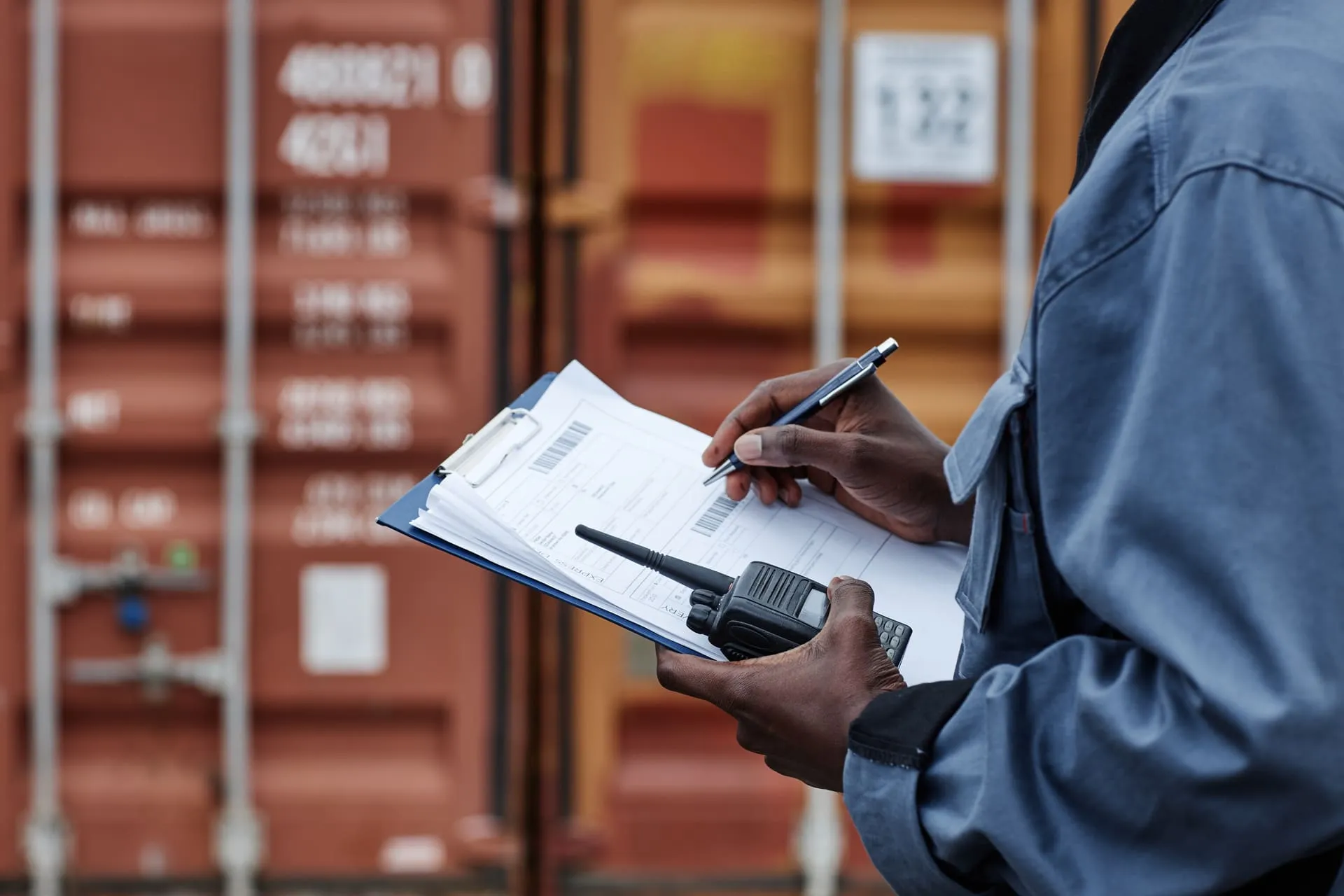 Travailleur devant des containers qui vérifie les commandes