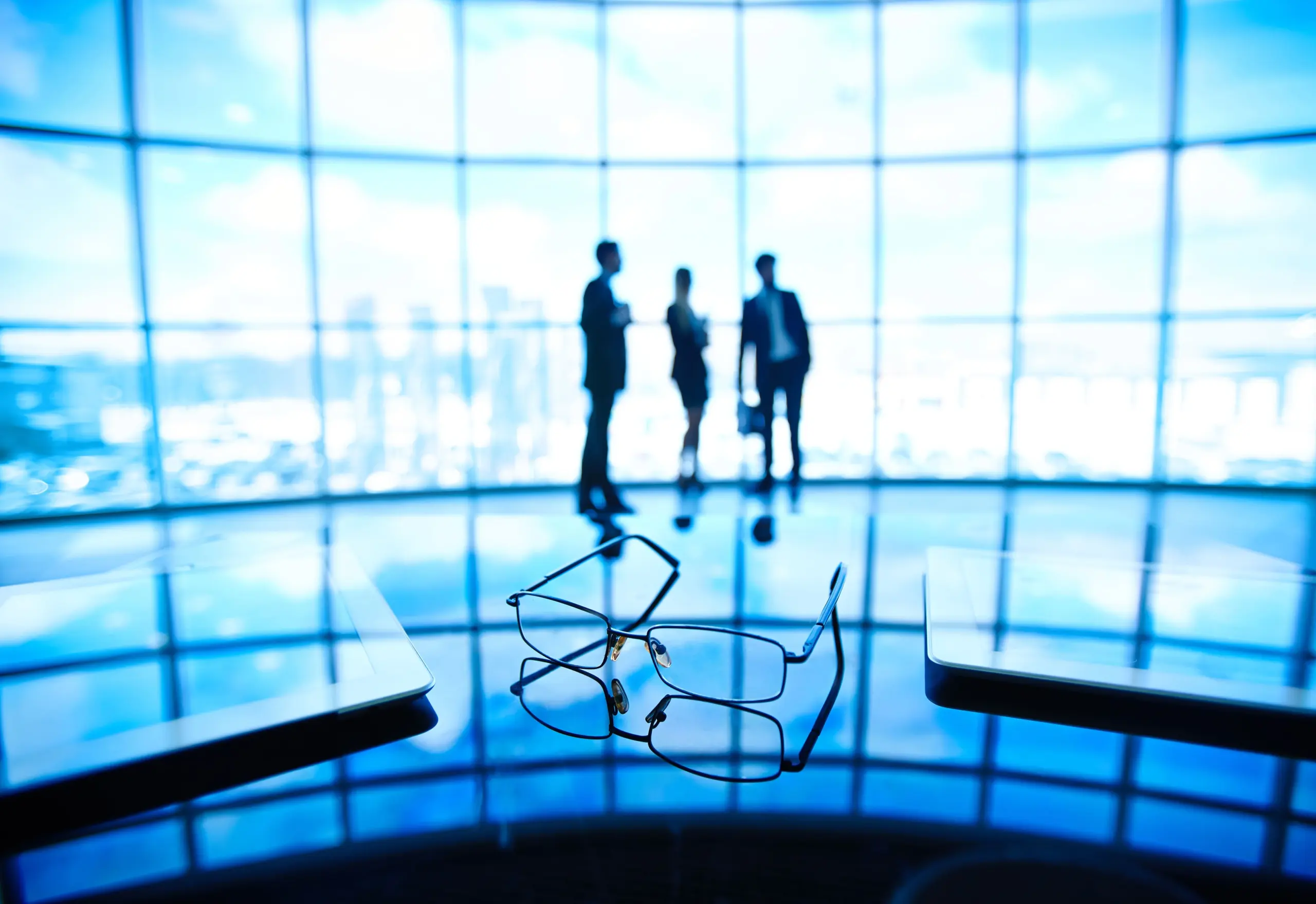 3 people chatting in front of a large window