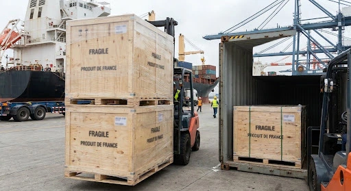 Chargement sécurisé de caisses en bois de vin français "Produit de France" dans un conteneur d'expédition pour l'exportation de vin français dans le monde au port de Bordeaux.